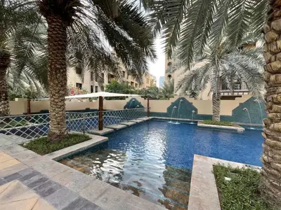 a swimming pool with palm trees in a resort at Old Town- Heart of Downtown. in Dubai