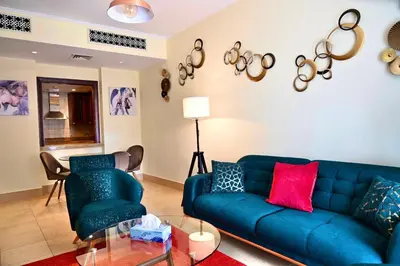 a living room with a blue couch and two chairs at Old Town- Heart of Downtown. in Dubai
