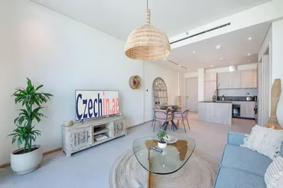 a living room with a blue couch and a glass table at Beautiful, Stylish and Peaceful 1BD in JVC in Dubai