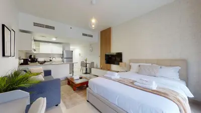 a bedroom with a large white bed and a kitchen at DA84 - Chic Studio in Dubai Arch Tower in Dubai