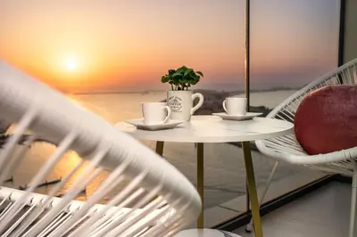 a table with two cups and a plant on a balcony at prime retreats - beach vista Emaar in Dubai