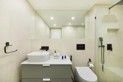 a white bathroom with a sink and a toilet at Maison Privee - Balinese Style Apt in the Heart of Downtown Dubai in Dubai