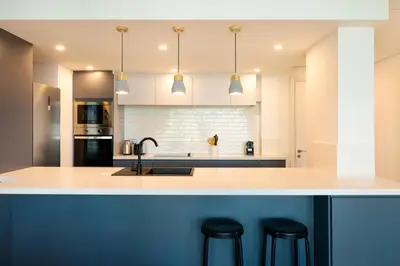 a kitchen with white cabinets and a counter with stools at Maison Privee - Balinese Style Apt in the Heart of Downtown Dubai in Dubai