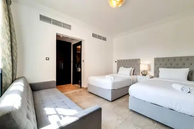 a hotel room with two beds and a couch at Whispering Pines, JGE - Exquisite Three Bedroom Villa in Dubai
