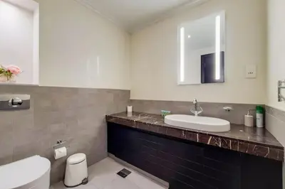 a bathroom with a sink and a toilet and a mirror at Whispering Pines, JGE - Exquisite Three Bedroom Villa in Dubai