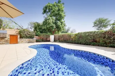 a swimming pool with blue tiles in a backyard at Whispering Pines, JGE - Exquisite Three Bedroom Villa in Dubai