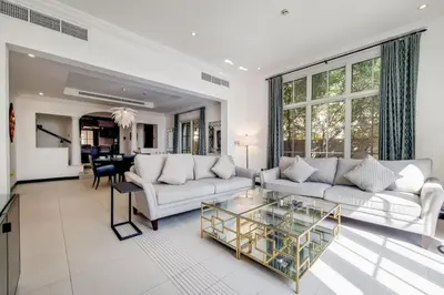 a living room with a white couch and a glass table at Whispering Pines, JGE - Exquisite Three Bedroom Villa in Dubai
