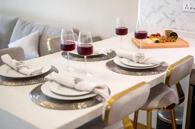 a table with two glasses of wine and a plate of food at Luxury Apt - Rooftop Pool - City View in Dubai