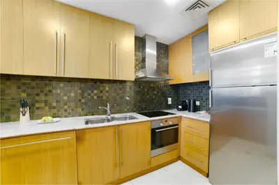 a kitchen with wooden cabinets and a stainless steel refrigerator at Vacay Lettings - Iris blue spectacular Marina view Apartment in Dubai