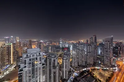 a night view of a city with tall buildings at Paramount Midtown Deluxe 1 BR Apartment with Full Burj-Khalifa View in Dubai