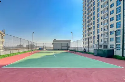 a tennis court in front of a tall building at The Smart Concierge - DEC Tower in Dubai