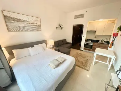 a bedroom with a large white bed and a living room at Super Elegant studio apartment-Sparkle tower By SWEET HOMES in Dubai