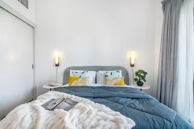 a bedroom with a bed with a blue blanket and pillows at The Smart Concierge - Sparkle tower in Dubai
