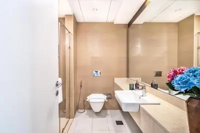 a bathroom with a toilet and a sink and a vase of flowers at The Smart Concierge - Sparkle tower in Dubai