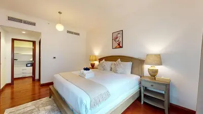 a bedroom with a large white bed and a night stand at Stylish 2-Bed Apt Burj Khalifa and Fountain Views in Dubai