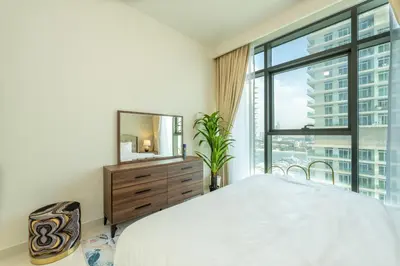 a bedroom with a bed and a mirror and a window at Emaar Beach Vista Tower 1 2BHK FAHH in Dubai