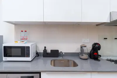 a kitchen counter with a microwave and a sink at Nice Studio in JVC - Pool & Gym in Dubai