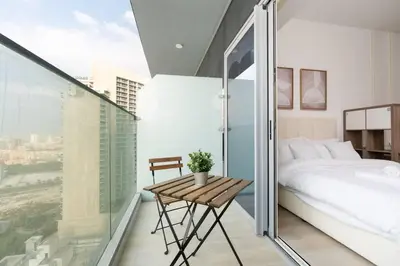 a bedroom with a bed and a table on a balcony at Nice Studio in JVC - Pool & Gym in Dubai