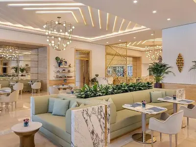 a living room with a couch and tables and a restaurant at Studio Apartment in The Palm Tower 5 Star Facilities in Dubai