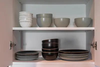a pantry with plates and bowls on shelves at Luxury studio in Discovery Gardens near metro in Dubai