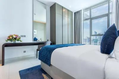 a bedroom with a bed and a desk and a window at The S Holiday Homes Canal view Studio and One Bedroom Apartments, Damac Maison Prive in Dubai