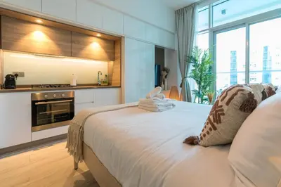 a bedroom with a large white bed and a kitchen at Stunning Apt Marina view with Balcony in Dubai