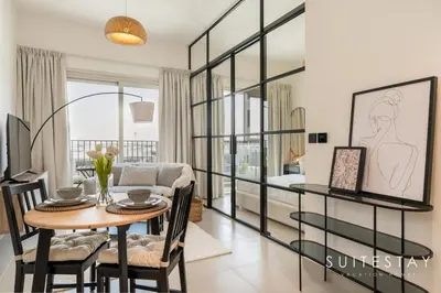 a dining room with a table and a living room at Chic One Bedroom Suite with Cozy Interiors in Dubai