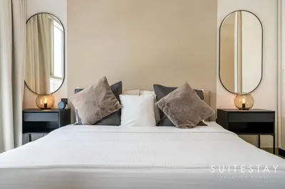 a bedroom with a white bed with two mirrors at Chic One Bedroom Suite with Cozy Interiors in Dubai
