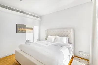 a white bedroom with a large bed with white sheets at Phenomenal 2BR with Scenic Sea-View from ALL rooms! in Dubai