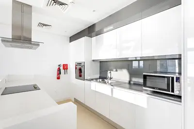 a white kitchen with white cabinets and a microwave at Phenomenal 2BR with Scenic Sea-View from ALL rooms! in Dubai