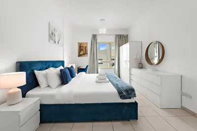 a bedroom with a blue and white bed and a mirror at Charming 1BR in The Greens, Near Metro in Dubai