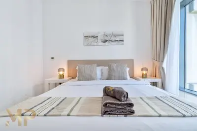 a white bedroom with a bed with towels on it at Marco Polo - Wake up to breathtaking Burj Khalifa views in Dubai