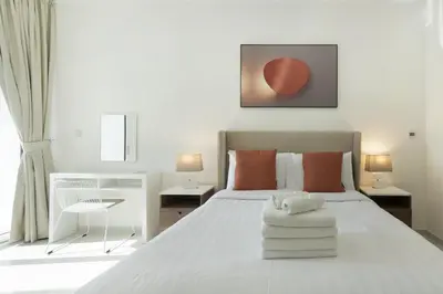 a bedroom with a large white bed with orange pillows at Tranquil 1BR apartment in Carson C, Damac Hills - Allsopp&Allsopp in Dubai