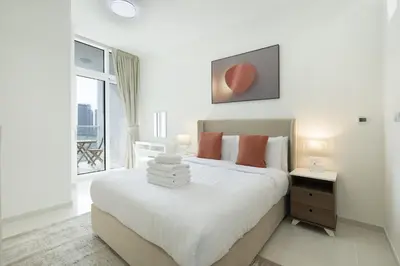 a white bedroom with a large bed and a window at Tranquil 1BR apartment in Carson C, Damac Hills - Allsopp&Allsopp in Dubai