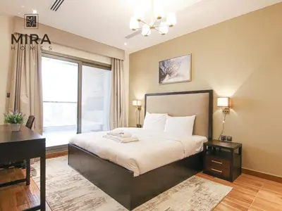 a bedroom with a bed and a desk and a window at Mira Holiday Homes - Lovely 1 bedroom in Downtown in Dubai