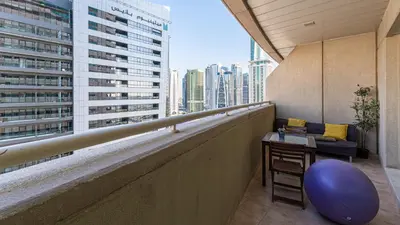 a balcony of a building with a blue chair and a table at Cosy 1 Bedroom Marina Apartment in Dubai