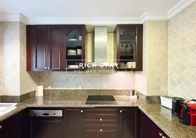 a kitchen with brown cabinets and a counter top at Upgraded 1BR in Downtown with Burj Khalifa View in Dubai