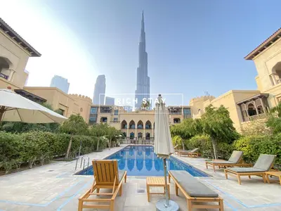 a pool with chairs and umbrellas in front of a building at Upgraded 1BR in Downtown with Burj Khalifa View in Dubai