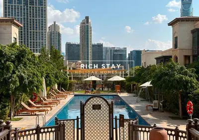 a pool with chairs and umbrellas in front of a city at Upgraded 1BR in Downtown with Burj Khalifa View in Dubai