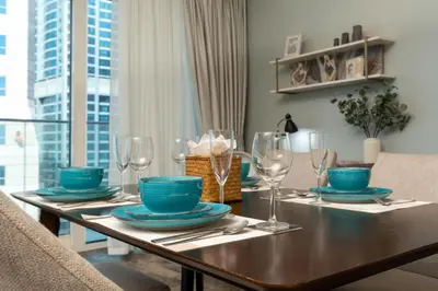 a dining room table with blue plates and wine glasses at White Sage - Fendi Apartment With Full Palm Jumeirah View in Dubai