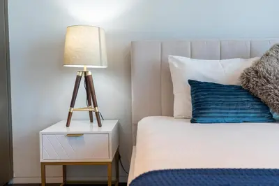 a bed with a night stand with a lamp on it at White Sage - Fendi Apartment With Full Palm Jumeirah View in Dubai