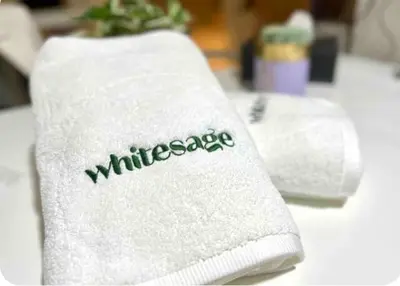 a white towel with the word wilderness written on it at White Sage - Fendi Apartment With Full Palm Jumeirah View in Dubai