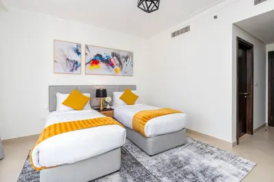 two beds in a white room with yellow pillows at Ultimate Stay / 7 people / Spacious / Dubai Creek with Marina Views in Dubai