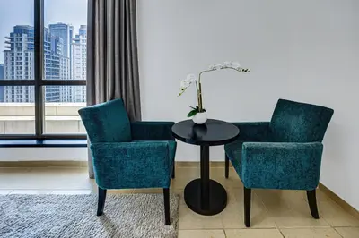 two chairs and a table in a room with a window at Comfy 1BD family apartment in Shams JBR in Dubai
