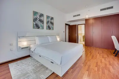 a bedroom with a large white bed and wooden floors at Cozy 2 BD in Bahar JBR 24 floor in Dubai