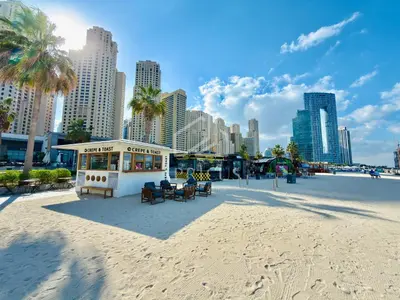 a building on the beach with a city in the background at Cozy 2 BD in Bahar JBR 24 floor in Dubai