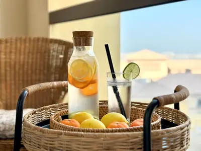 a basket of fruit with a bottle of lemonade and a drink at Family apartment next to the beach in Dubai