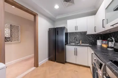 a kitchen with white cabinets and a black refrigerator at Ultra Luxury Palm - Free 5-star Beach Resorts Access in Dubai