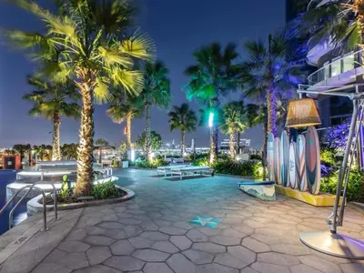 a resort patio with palm trees and tables at night at Cosmos Living 1 Bedroom Paramount Hotels in Dubai