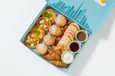 a blue lunch box filled with pastries and other foods at Cosmos Living 1 Bedroom Paramount Hotels in Dubai